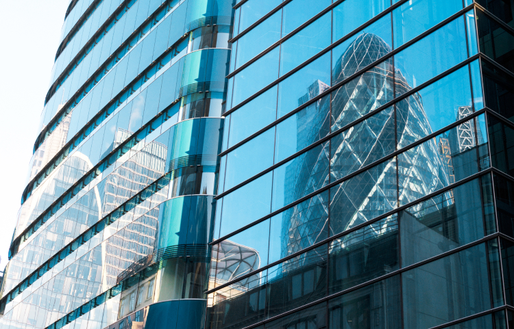 Un reflet d’un gratte-ciel est vu dans les fenêtres d’un autre immeuble de bureaux.